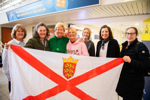 Jersey airport arrivals hall. Two of the rowers of Team Intrepid 232 return to the island following Atlantic 2024 and setting a new world record for the oldest women's fours crew to complete the challenge.         Rosemary Satchwell, Alison Smithurst, Julie Brady and Helene Monpetit finished the 3,000-mile rowing race in 58 days, 12 hours and 30 minutes, the 10th boat in the Women’s Class and 28th in all boats.    Alison Smithurst  (third from left) and Julie Brady (fourth from left/pink top) welcomed by friends                            Picture: ROB CURRIE