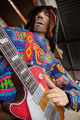 BOF Battle of Flowers 2024. Grouville BOF shed. Building of float called Pop Goes The 60s. Dean Maryon, who had a big part in the making of \"Roger\" the guitarist, playing a replica of a Gibson guitar and covered in pine cones, beans, seeds and ormer shell (on the neck of the guitar                                  Picture: ROB CURRIE