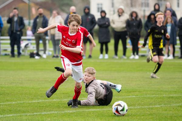 Football at FB Fields. Jersey Primary schools football festival. Jersey A (red) V Gloucester A (black). L>R Mason Woodley, on his way to scoring, avoiding goalkeeper Frankie Lake                                 Picture: ROB CURRIE