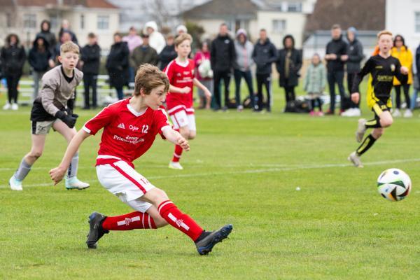 Football at FB Fields. Jersey Primary schools football festival. Jersey A (red) V Gloucester A (black). L>R Mason Woodley, on his way to scoring, avoiding goalkeeper Frankie Lake                                 Picture: ROB CURRIE